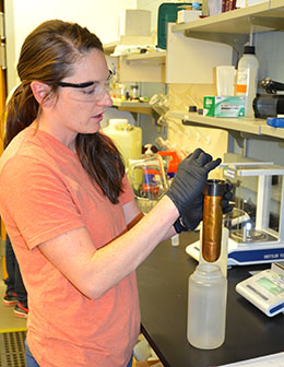 woman in safety goggles working at lab table