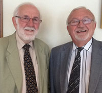 two older men in ties and jackets standing beside each other