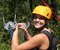young woman in helmet holding onto a zip line bar