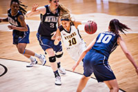 Cowgirl basketball player running with ball between opponents