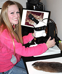 young woman seated at microscope