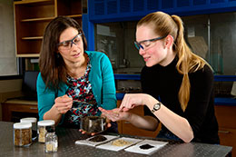 two women wearing safety glasses examining samples on a table