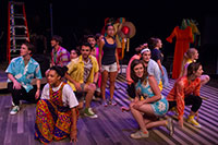 women and men in colorful clothing crouching on a stage