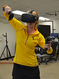 woman standing, wearing virtual reality headset and holding controllers