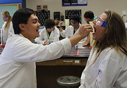 young man in lab coat using swab in the mouth of a young woman in lab coat