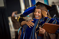 woman in cap and gown being hugged by someone else in a cap and gown