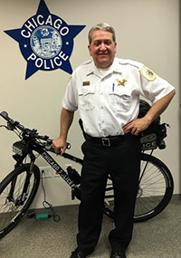 man in uniform standing beside bicycle with Chicago PD logo behind him