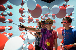 children wearing special glasses in a room with large 3d spheres in it