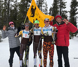 five men outdoors with UW flag, three in Nordic ski uniforms