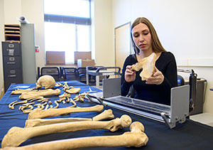 woman sitting at table examining bones