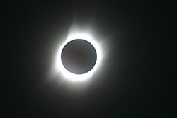 complete solar eclipse with corona of light around dark disc of moon