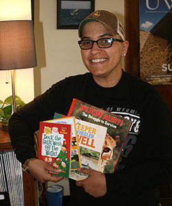 young woman displaying an armload of children's books