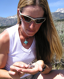 woman looking at baby bird in the palm of her hand