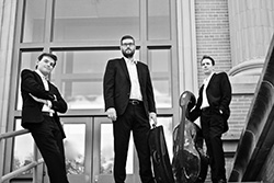 black and white photo of three men in formal clothing, one with a musical instrument case