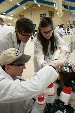 three people in lab coats working on a device