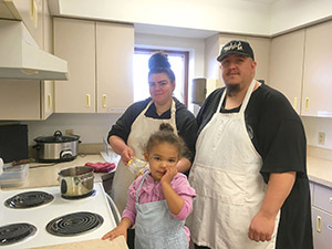 woman, child and man wearing aprons in a kitchen