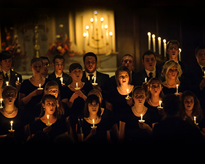 group of people standing in the dark with lit candles