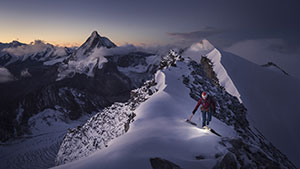 person walking on a snowy mountain ridge at twilight
