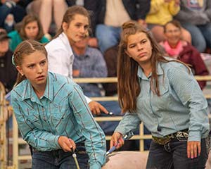 two girls in a livestock ring in front of an audience