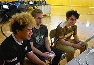 three people playing video games in a gymnasium