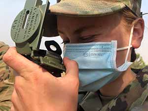 woman in camo fatigues looking at equipment