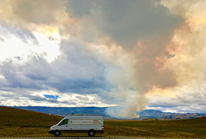 large van with smoke-filled sky behind it