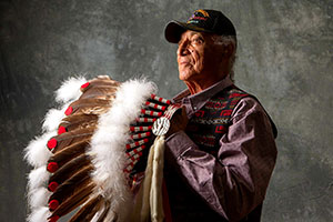 Native American man holding a traditional headdress