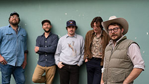 five men in a row near a wall