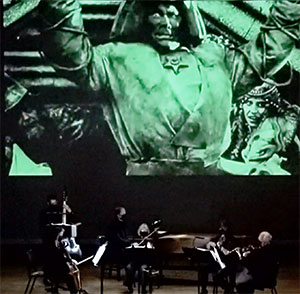 musicians playing beneath a huge banner with a green golem