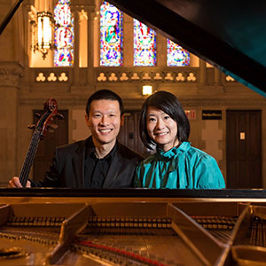 two people sitting at a grand piano