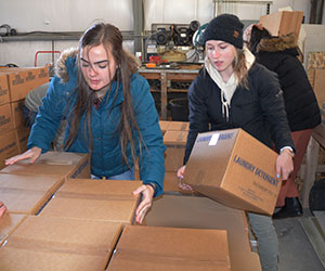 two woman stacking boxes