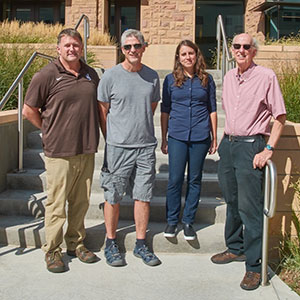 four people posing together outside