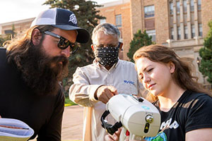 three people working with scientific equipment outside