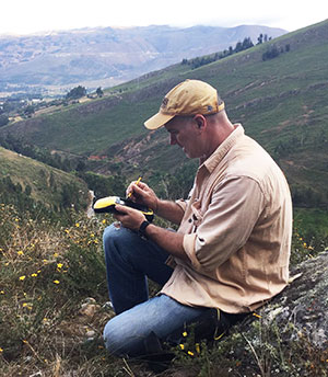 man sitting on mountainside working on something