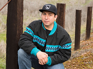 man crouching in front of fence line