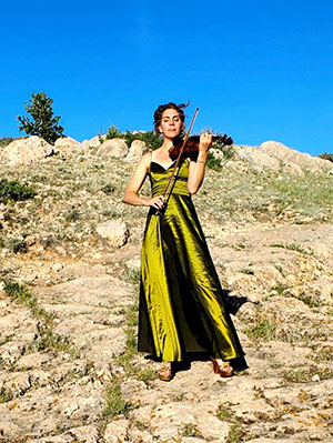 woman playing violin outdoors in rocky area