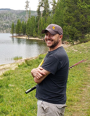 man with fishing rod standing by water