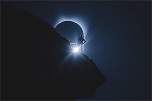 climber on mountain during solar eclipse
