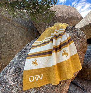 wool blanket in gold, brown and white with UW logo woven into it