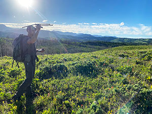 man carrying a satellite tracker in the mountains