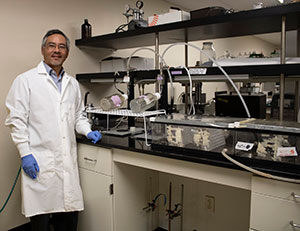 man in front of counter and shelves with equipment and tubes attached
