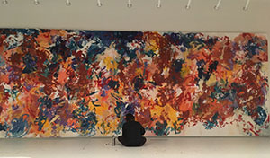 person seated on the floor in front of a large painting