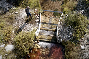 man by an irrigation gate on a stream