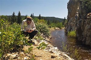 man crouched by a stream