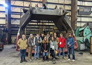 group of people in front of huge piece of equipment