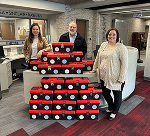 three people with a large stack of red and black boxes