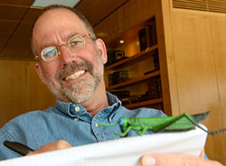 a man with a book with a toy grasshopper perched on it