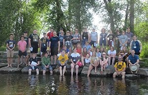 large group of people posing on a river bank