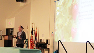 woman lecturing with image on screen behind her
