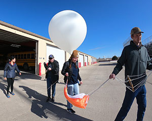 people carrying a weather balloon
